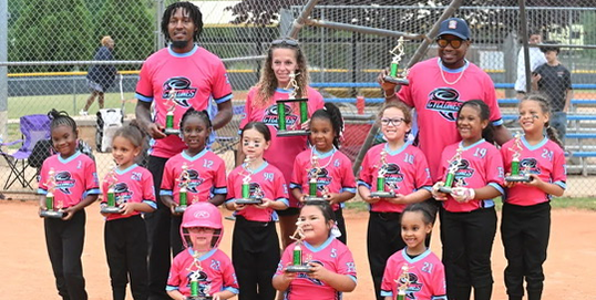 Young ladies in pink jerseys showing off championship trophys