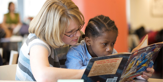 Woman reading a book to a child.