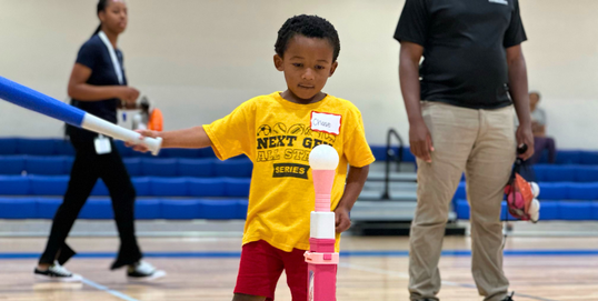 Young boy with plastic bat about to hit a ball on a tee